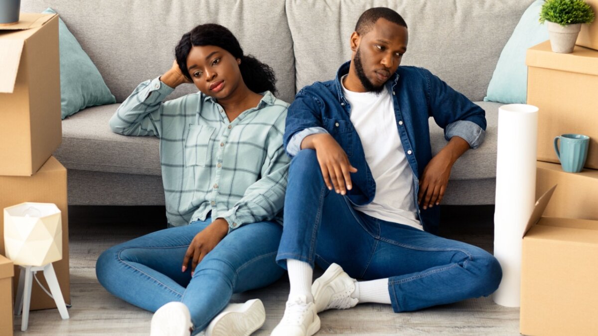 Portrait Of Tired Black Couple Sitting On Floor Exhausted After Moving To New Apartment, Upset Millennial African American Spouses Having Problems During Relocation To Own House, Free Space
