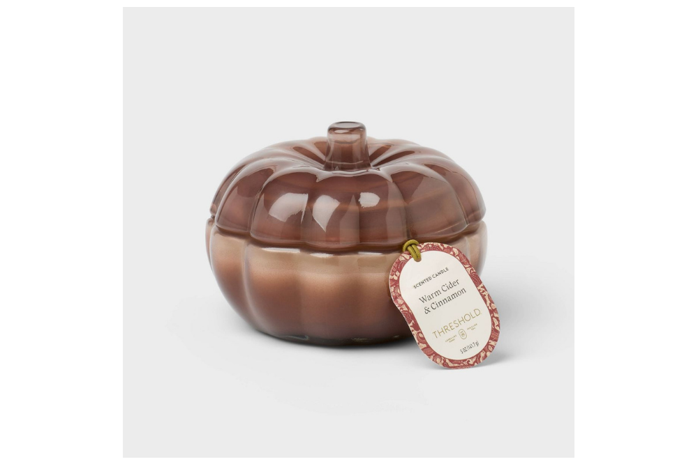Pumpkin-shaped glass candle jar with a warm cider and cinnamon label