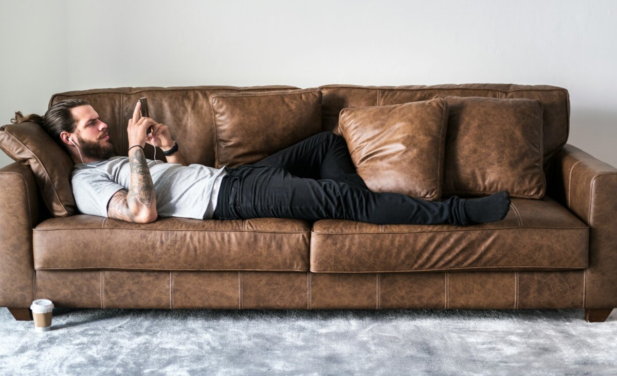 lazy man on sofa with phone and earbuds