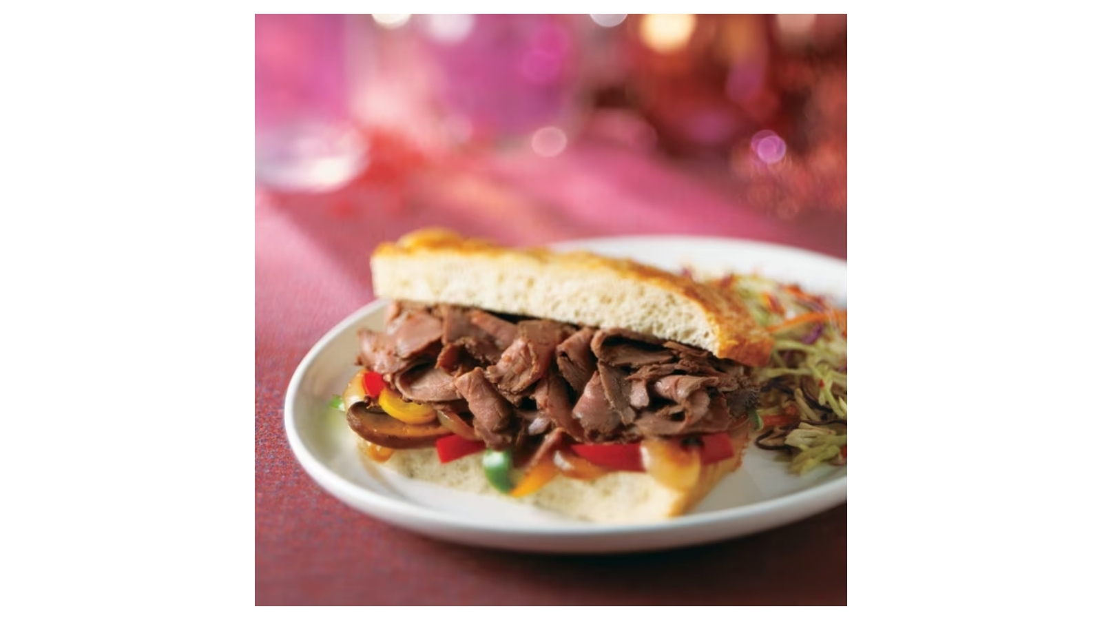 Philly steak sandwich with peppers and onions on a white plate
