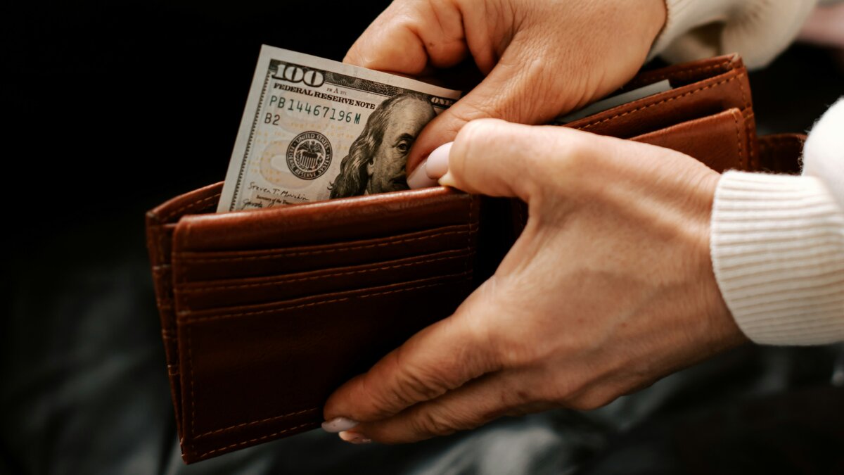 Woman pulling $100 bill out of her wallet
