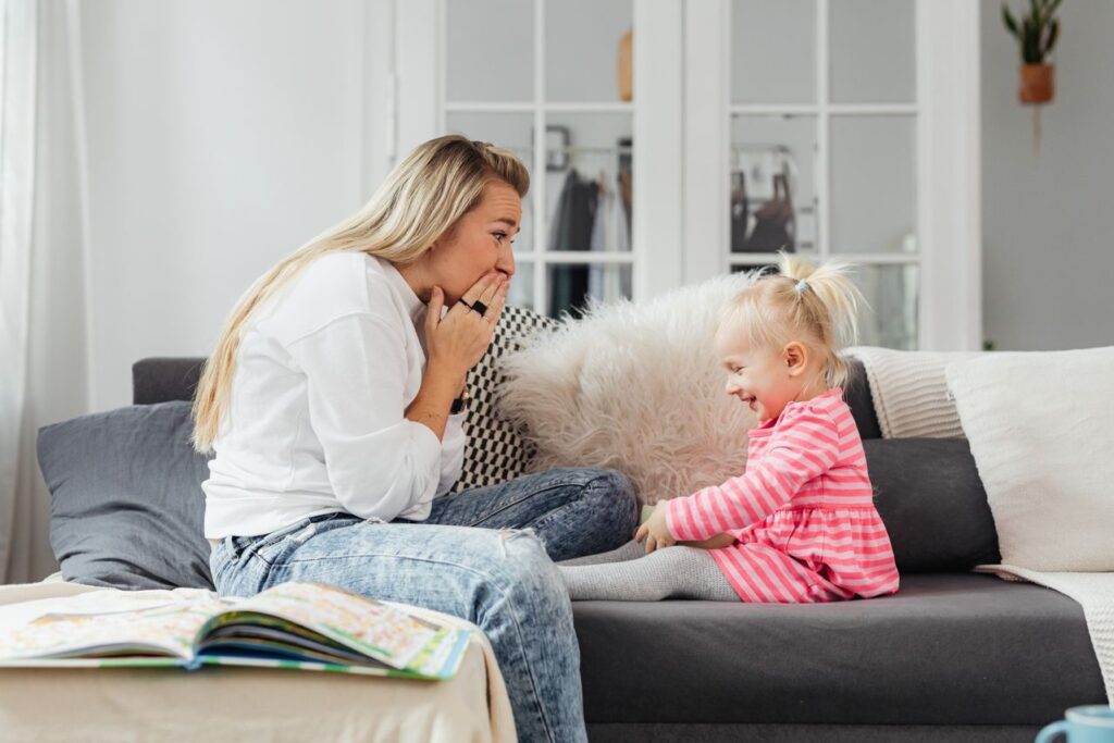 Mother reading and laughing with young daughter