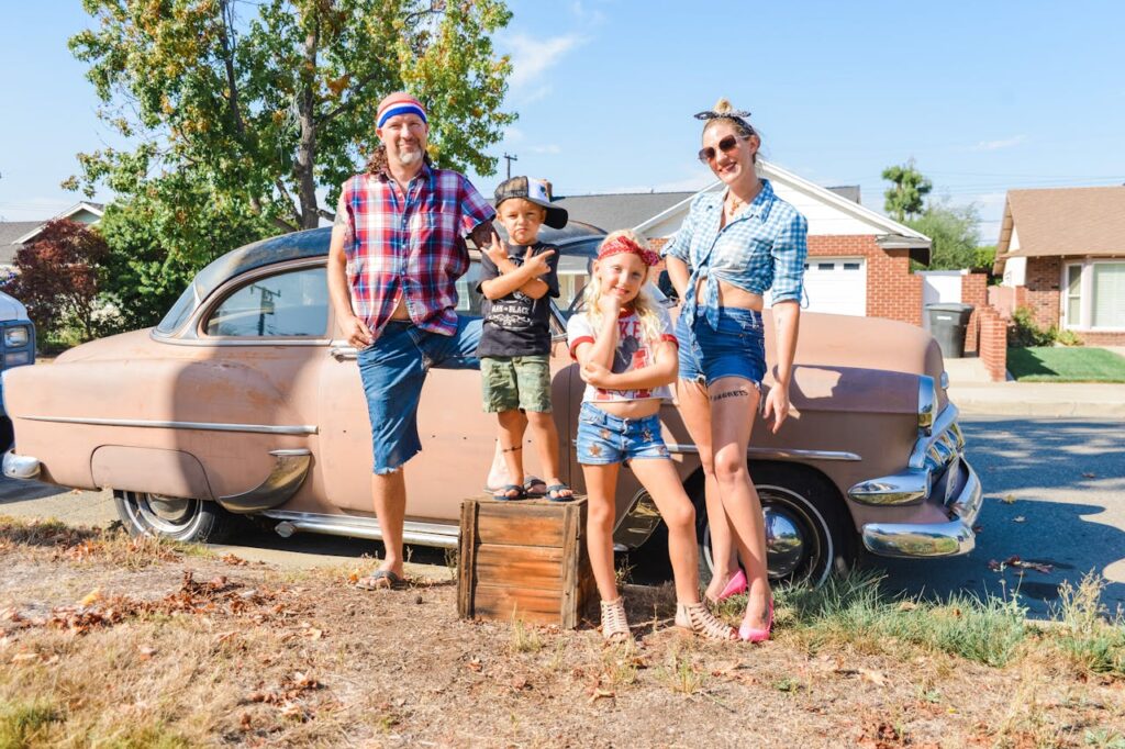 Family in retro outfits beside a vintage car