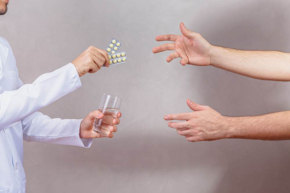 The physician gives medicine to the man. You can find the lowest prices on prescription medicines near you with SingleCare.