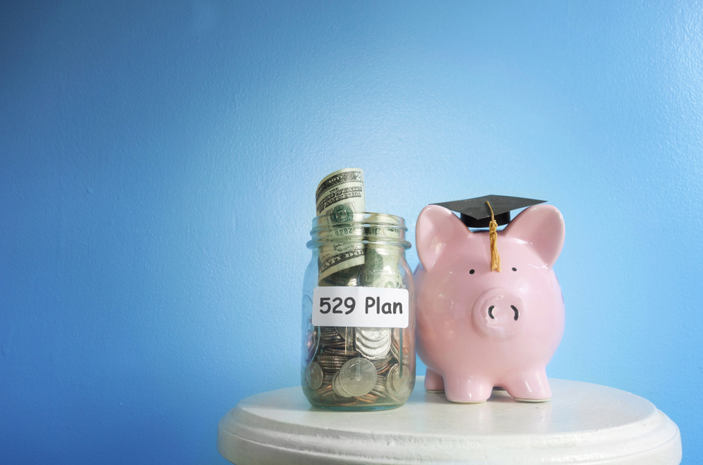 Piggy bank wearing a graduation cap beside a jar labeled 529 Plan