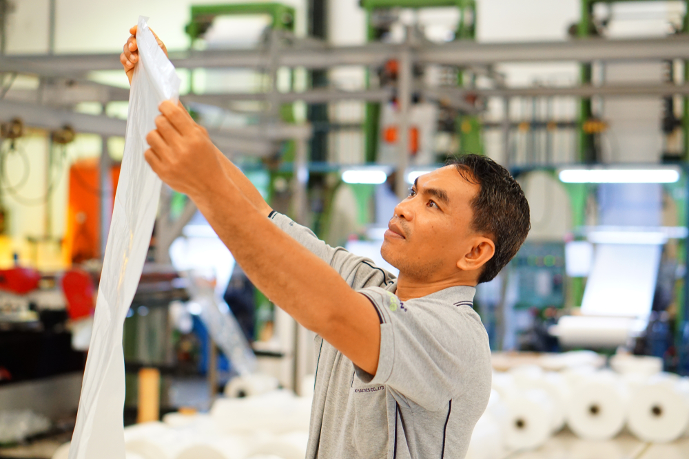 Packaging quality technician inspecting plastic film in a manufacturing plant