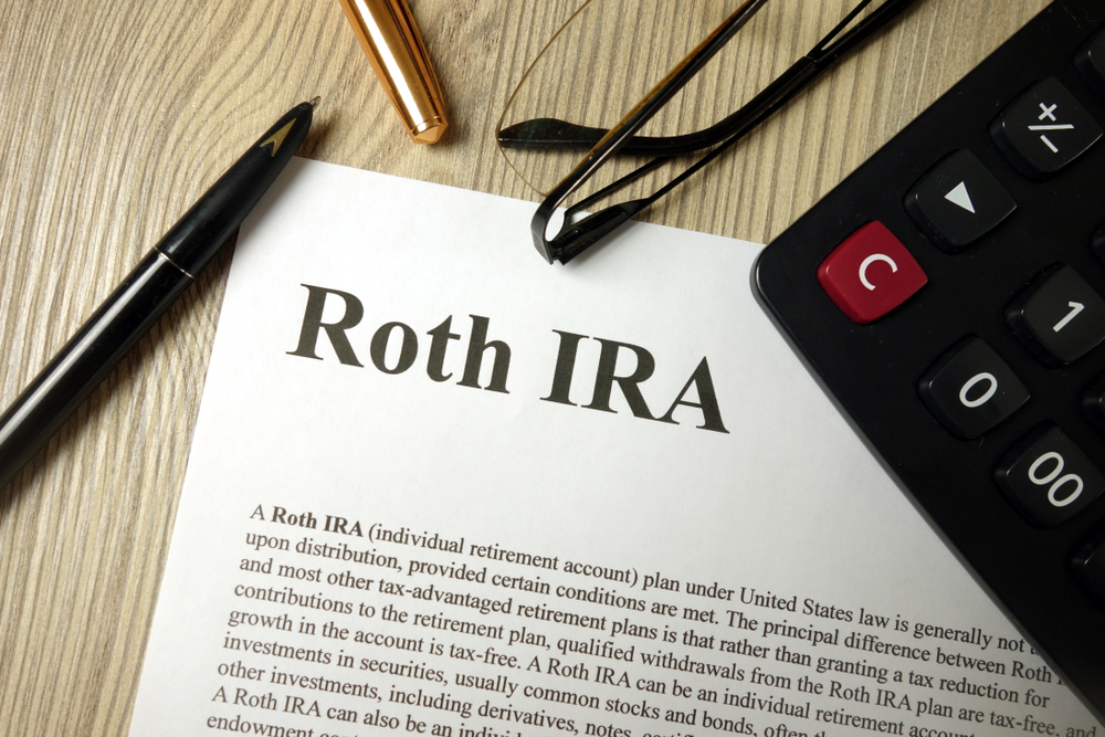 Roth IRA paperwork with a calculator, pen and glasses