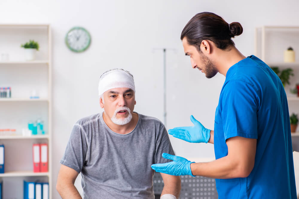 older man with bandage on head