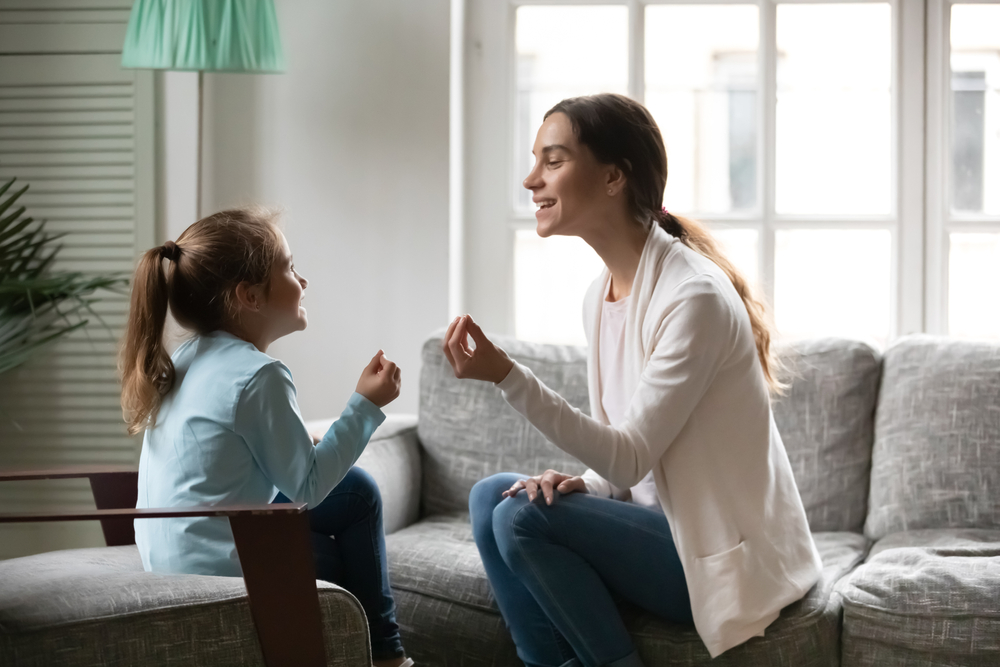 Speech therapist and young girl practicing mouth movements during a speaking lesson