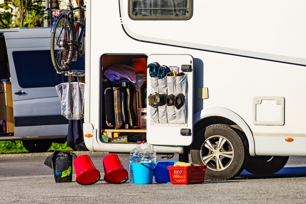 Motorhome with an open storage compartment, buckets, baskets and cleaning supplies arranged outside