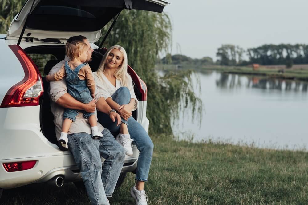 family sitting against an SUV trunk