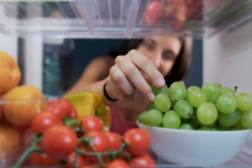 woman reaching for fresh food in fridge