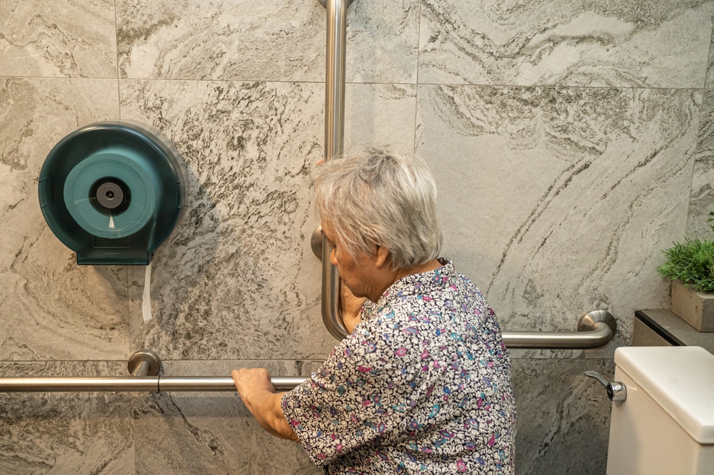 older person using grab rail in bathroom