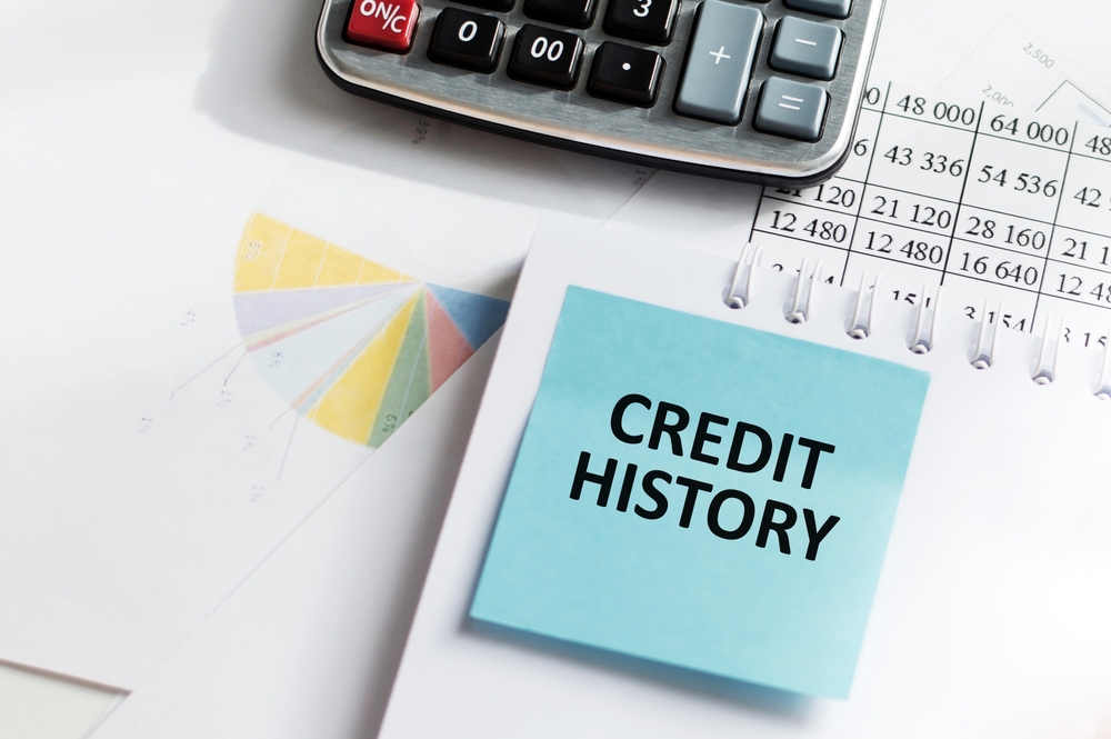 Blue credit history note beside a calculator and financial paperwork