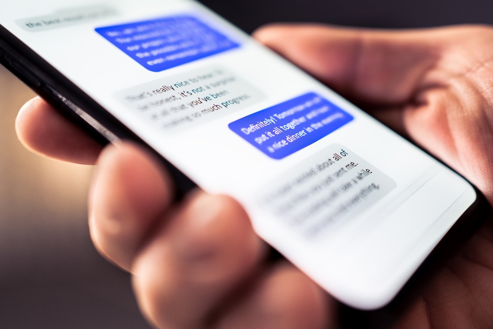 Hand holding a smartphone displaying a text-message conversation