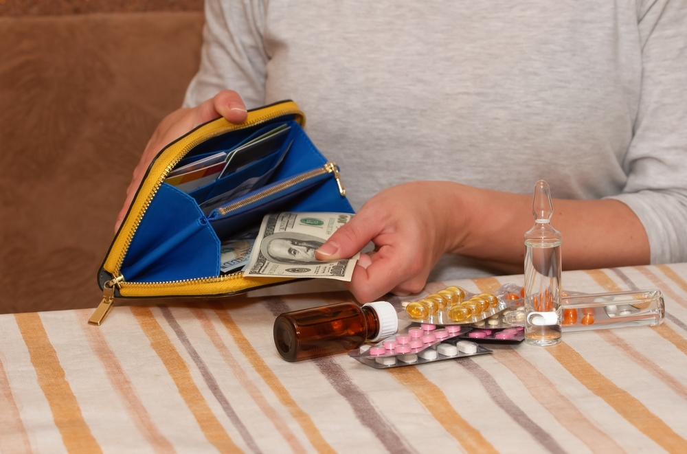 Woman taking US dollar bills from a wallet beside prescription medication