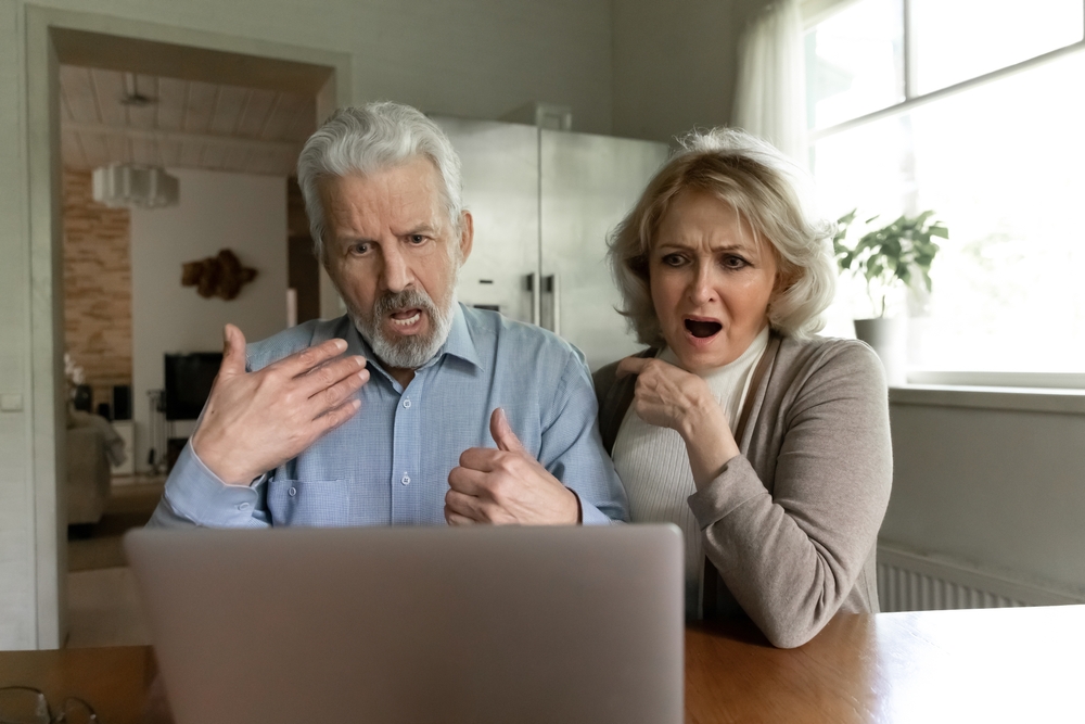 Older couple looking shocked at a laptop screen together
