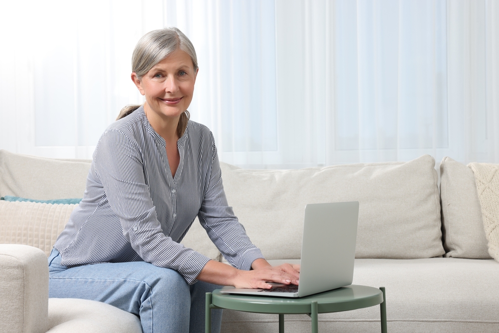 Woman using a laptop while sitting on a sofa at home