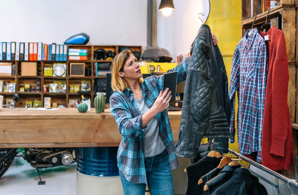 woman looking at leather jacket in thrift store