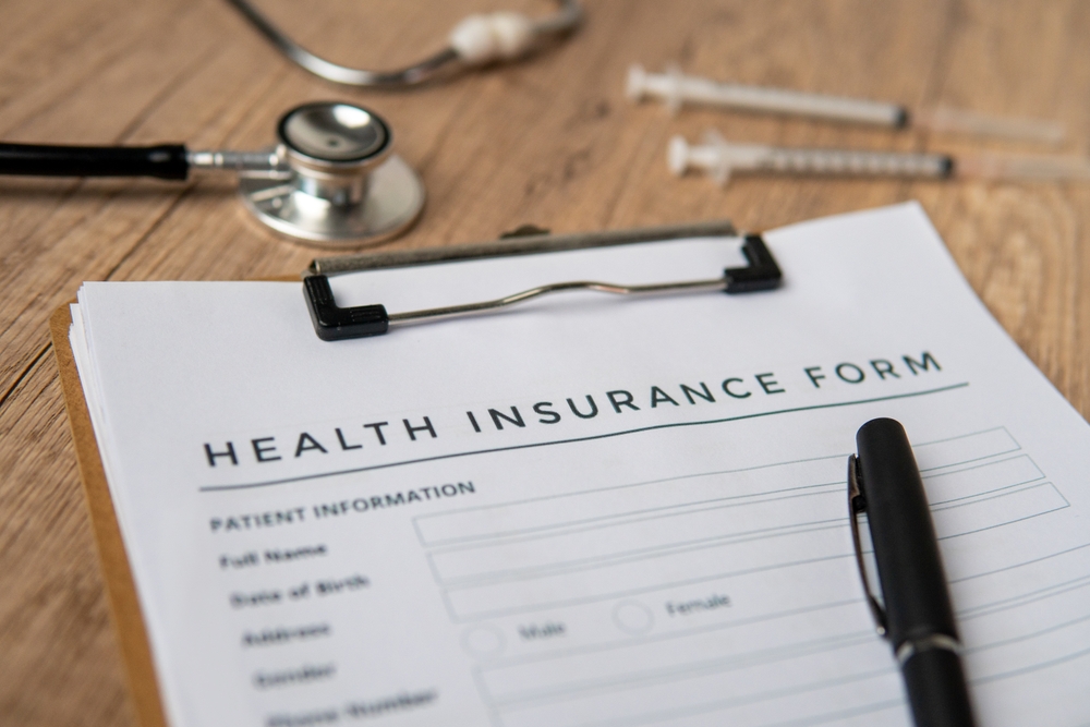 Health insurance form on a clipboard with a pen and stethoscope