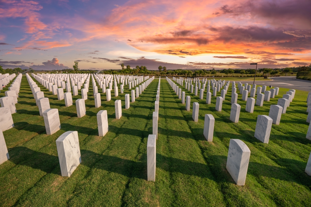 Rows of white headstones on carefully maintained grass in a veterans cemetery