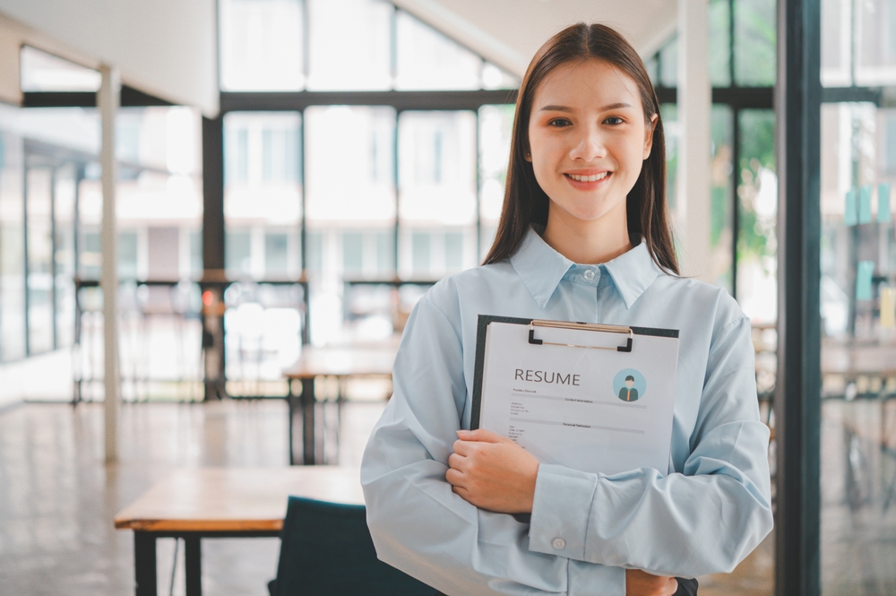 Woman holding a clipboard with her resume in an office