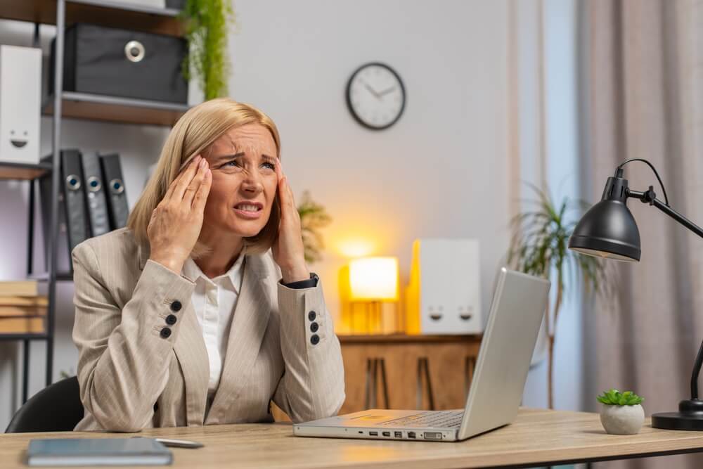 Overworked office employee rubbing temples at desk