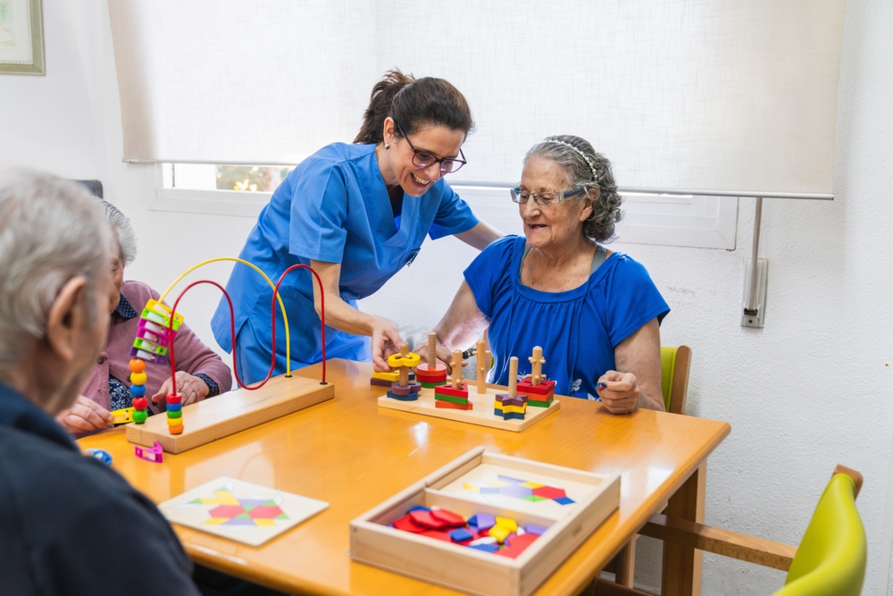 Care professional helping an older woman use colorful wooden activity pieces