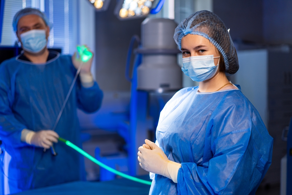 Surgical technologist preparing sterile operating room Surgical team preparing equipment in a clean operating room while wearing masks and protective clothing