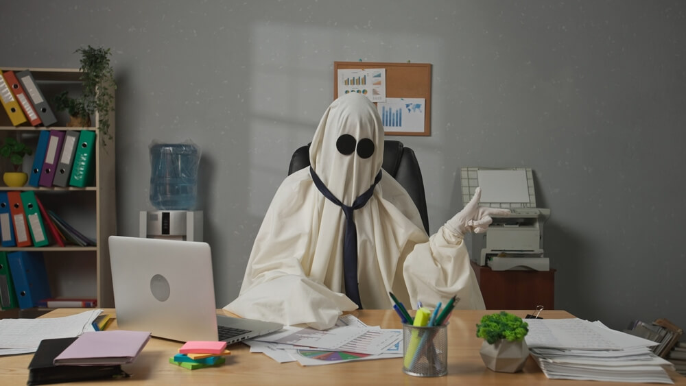 person dressed as ghost at computer