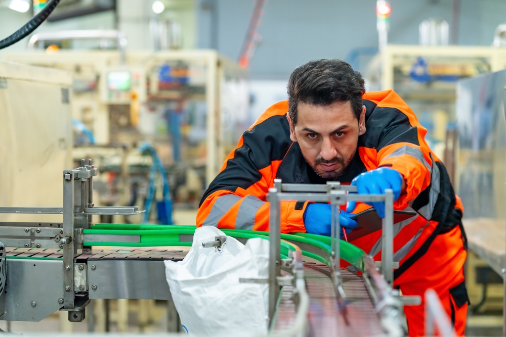 Industrial machinery mechanic repairing factory conveyor belt Industrial machinery mechanic repairing an automated conveyor belt on a factory production line