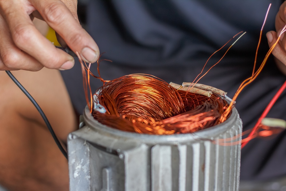 Electric motor repair technician working on copper windings Electric motor repair technician repairing copper wire windings inside an opened motor