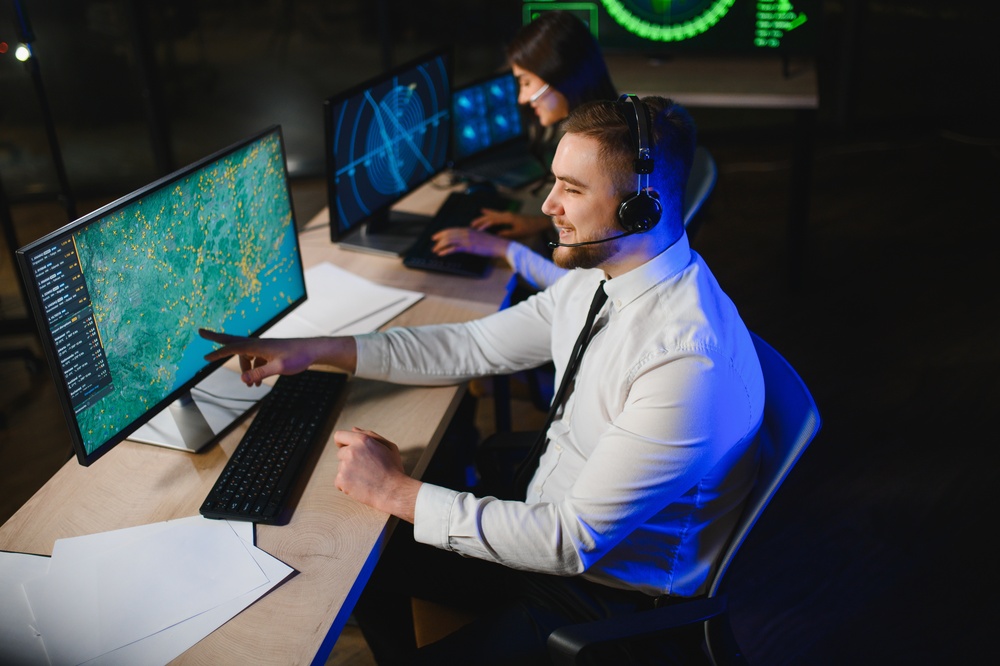 Air traffic controllers wearing headsets and monitoring radar screens in a control room