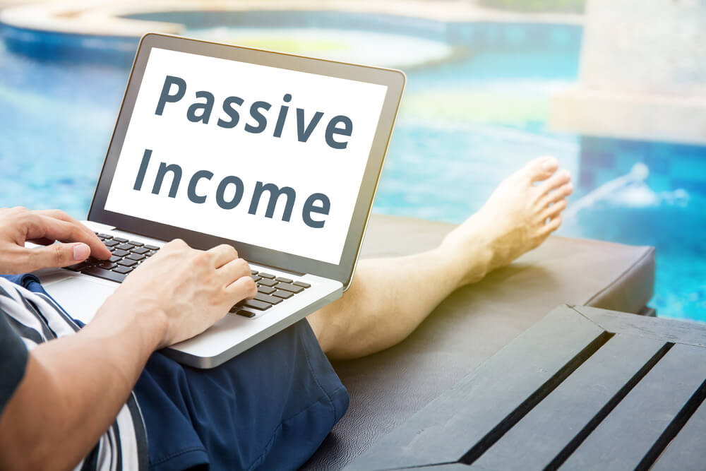 'Passive Income' word on man relaxing with his laptop