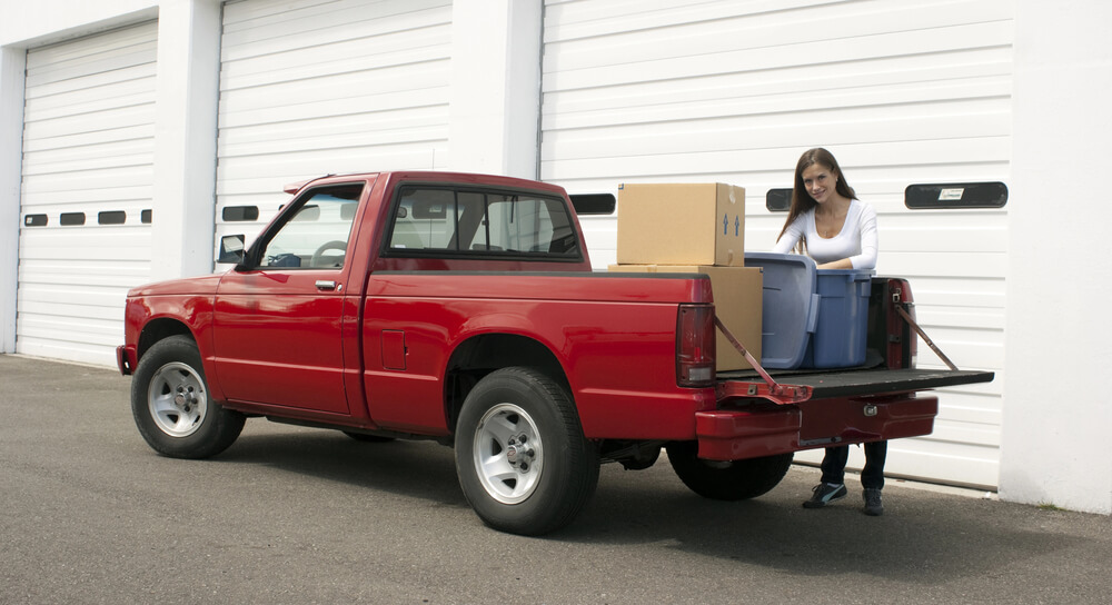 A woman pulls up to a storage facility to unload boxes in an article about free movers and moving help.