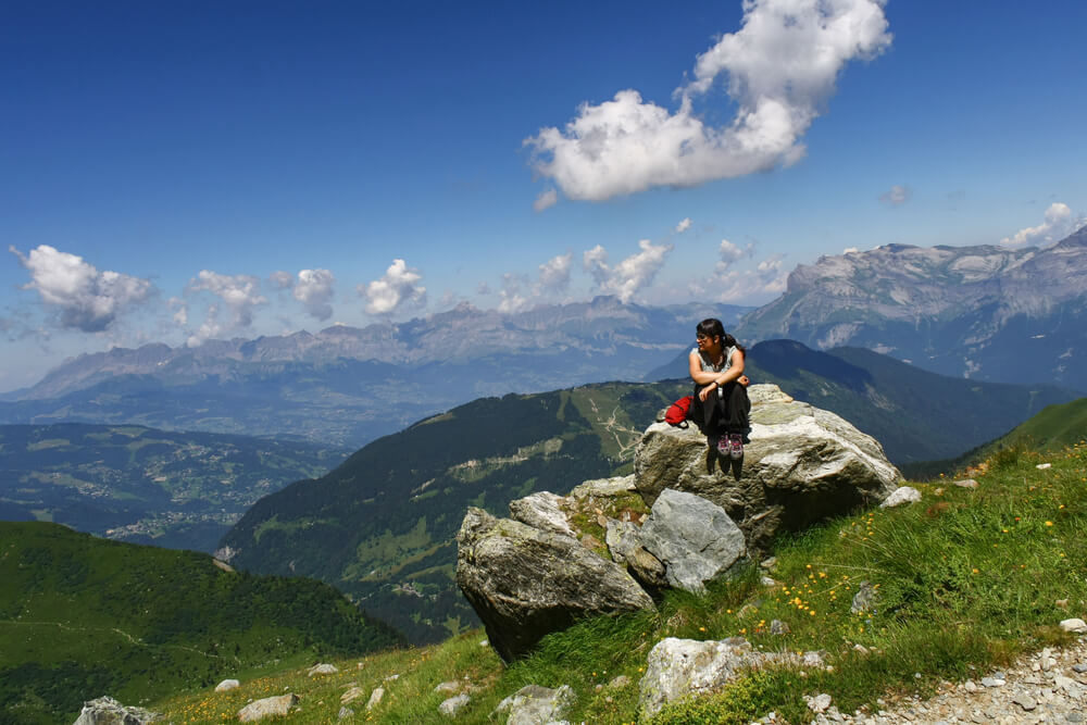 Woman seated on rocks in mountain, hiking alone