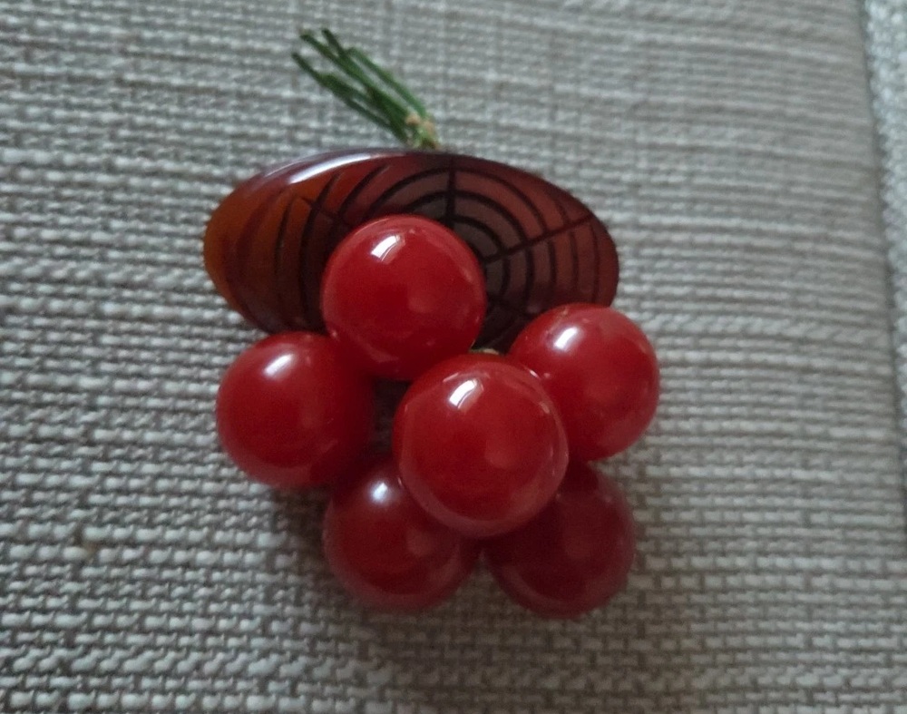 Red Bakelite cherry dangles hanging beneath a carved brown leaf and green stems
