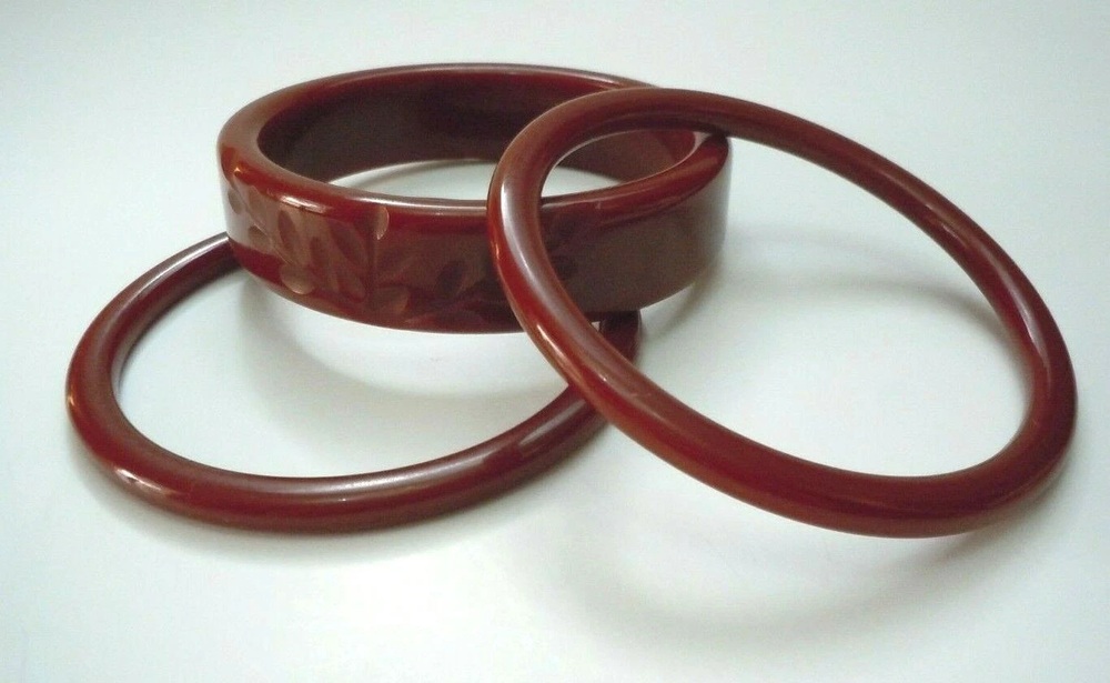 Three deep-red Bakelite bangles, including a wide carved bracelet and two narrow spacers