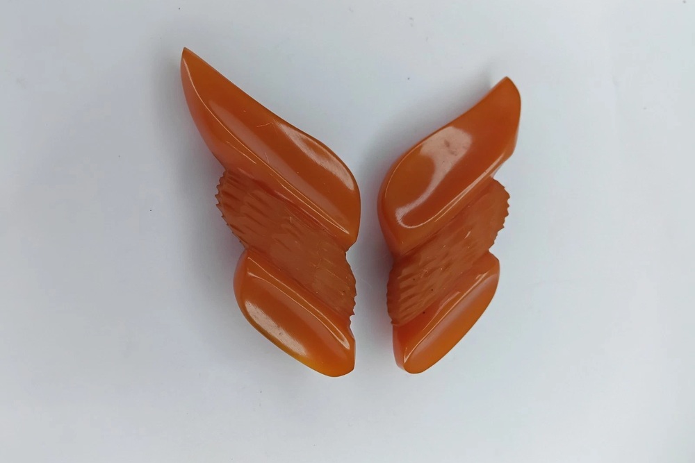 Matching orange Bakelite dress clips with sweeping geometric carvings