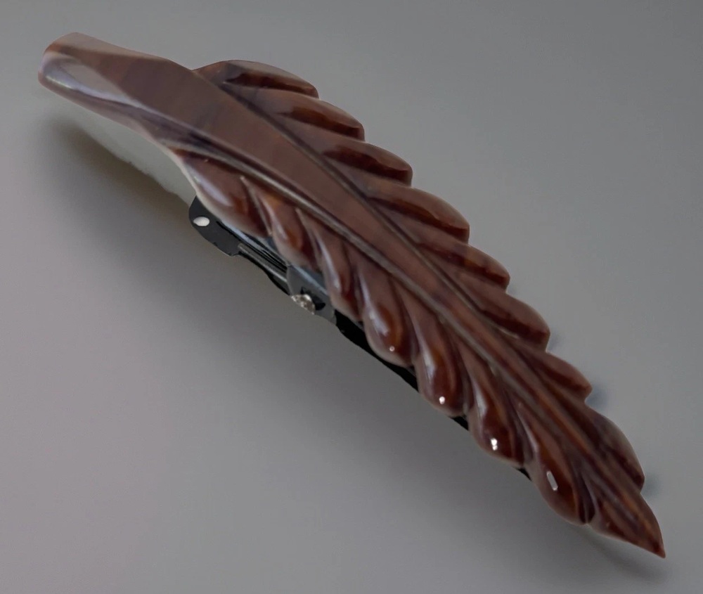 Brown Bakelite hair barrette carved in a long leaf shape with its metal clip visible