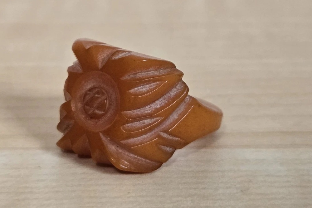 Butterscotch Bakelite ring with a raised carved floral face and sweeping curved sides