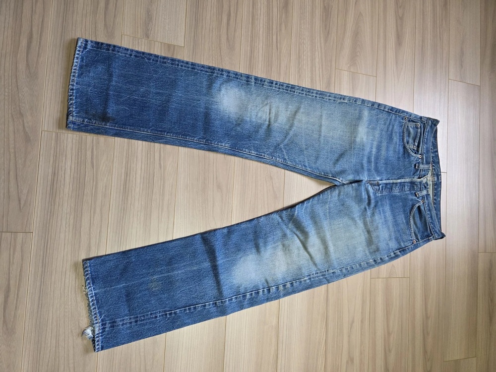 Vintage Big E Levi's 501 jeans laid flat on a wood floor