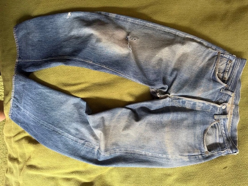 Original leather-patch-era Levi's 501XX jeans laid flat on green fabric