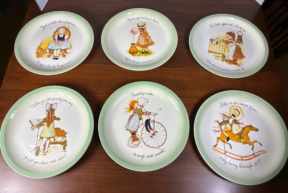 Six green-rimmed Holly Hobbie collector plates with illustrated scenes