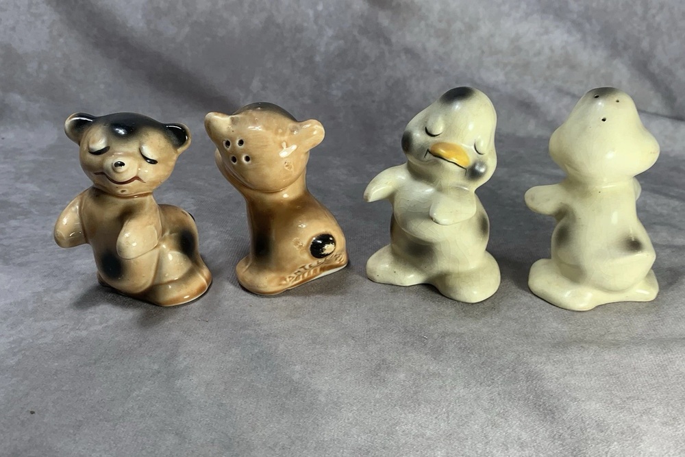 Van Tellingen bear and duck salt and pepper shakers arranged on gray fabric.