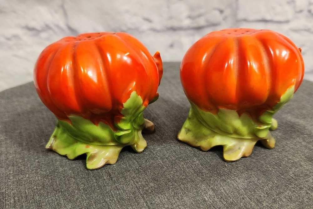 Royal Bayreuth tomato shakers with ribbed orange-red bodies and green leaf feet.