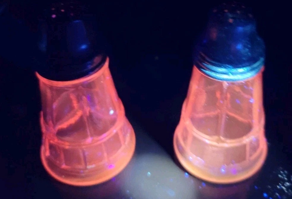 Jeannette Doric glass shakers glowing pink under ultraviolet light.