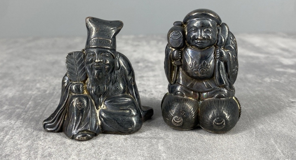 Antique Japanese silver figural shakers depicting two seated figures.