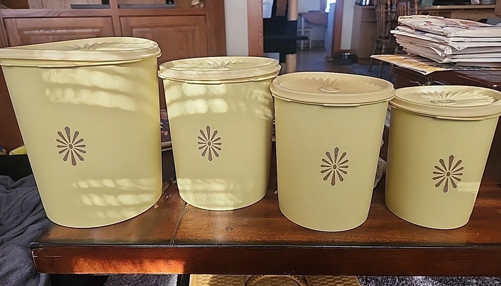 Four harvest gold Tupperware Servalier canisters with sunburst designs