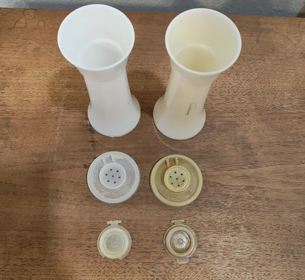 Two white hourglass Tupperware shakers with their lids removed